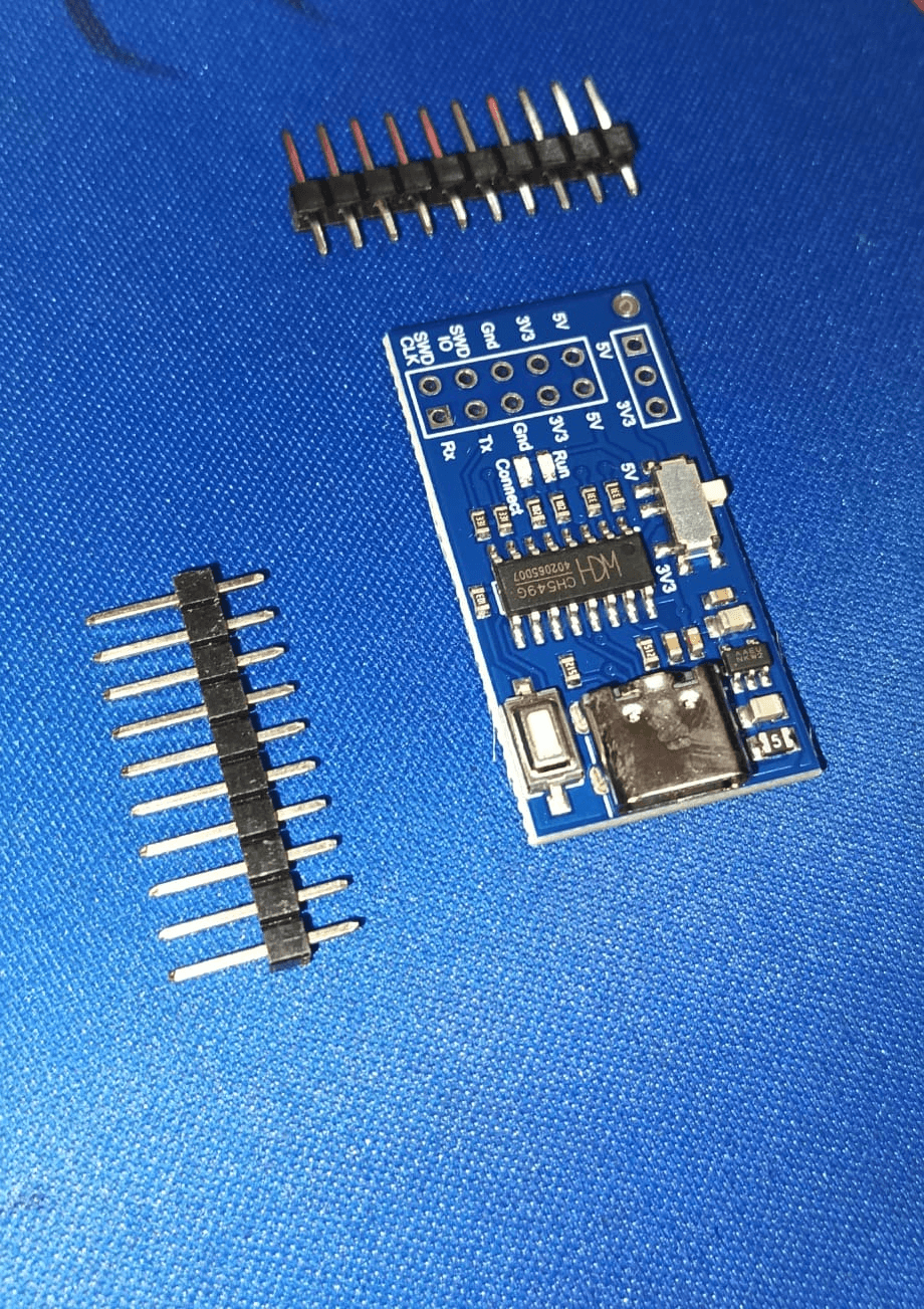 The WCH-Link clone board with two unsoldered header strips beside it, USB-C connector and slide switch visible, the SOP-16 chip marked CH549G