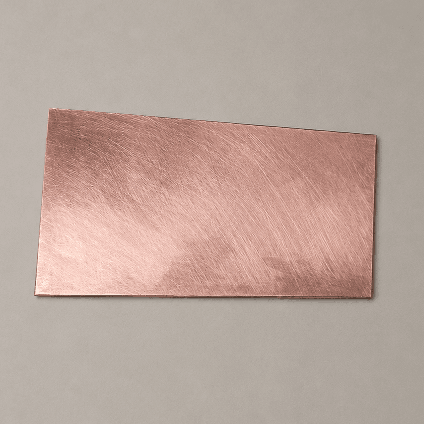 A small rectangle of bare copper clad board, scrubbed clean, on a plain grey background