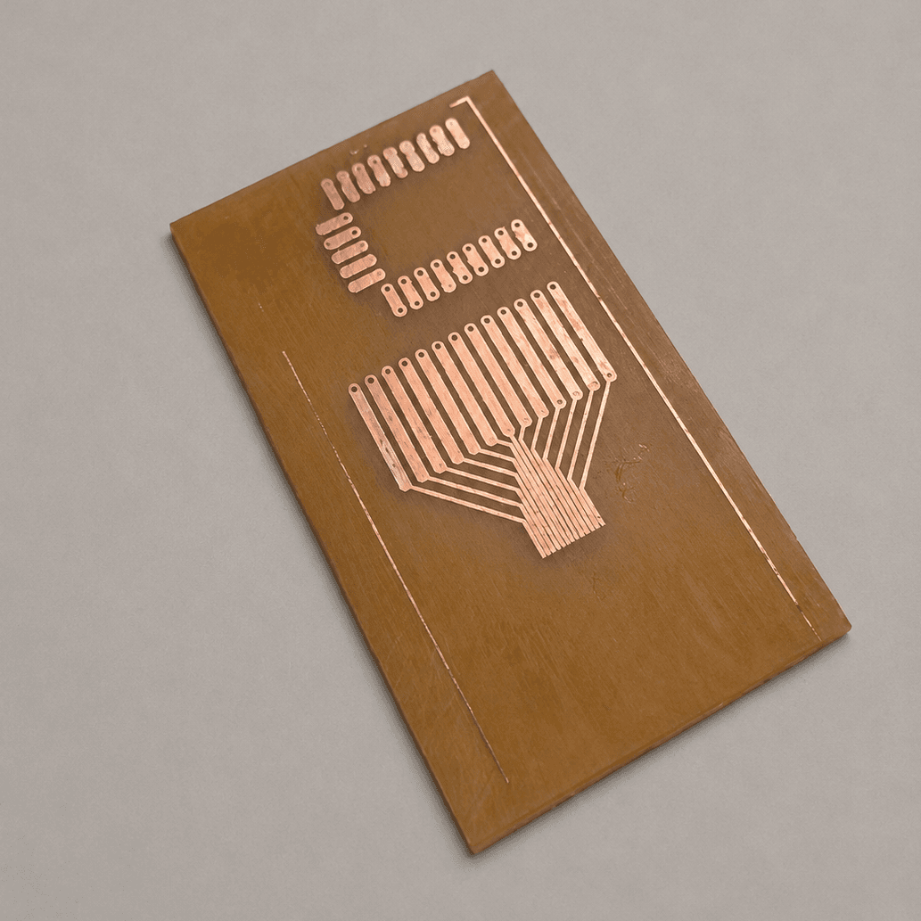 The finished etched board, copper traces and pads standing out against the pale substrate where the copper has been removed